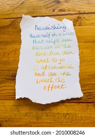 Nourishing yourself in a way that helps you blossom in the direction you want to go is attainable and you are worth the effort! Handwritten text. wooden table as background.