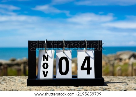 Nov 04 calendar date text on wooden frame with blurred background of ocean.