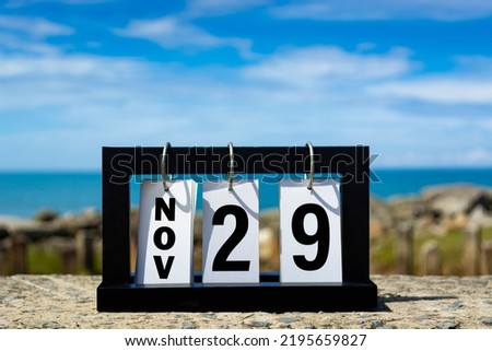 Nov 29 calendar date text on wooden frame with blurred background of ocean.