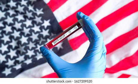 Novel Coronavirus Outbreak In USA Concept. Nurse Hand Holding Blood Test Tube With Label 2019-nCoV Over Flag Of The United States Of America. Coronavirus Diagnosis, Laboratory Testing For 2019-nCoV.