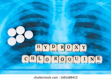 Novel Covid-19, Coronavirus. Infected Lungs Radiology Blue Image Background, With White Pills On It. Hydroxy Chloroquine Written With Wooden Letters.