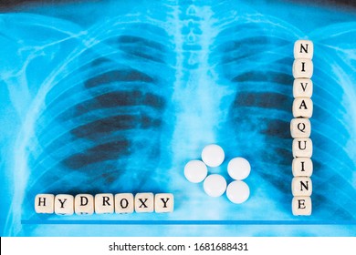 Novel Covid-19, Coronavirus. Infected Lungs Radiology Blue Image Background, With White Pills On It. Hydroxy Chloroquine Written With Wooden Letters.