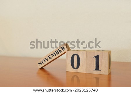 November 1, Date design with calendar cube on wooden table and white background.