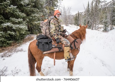 NOVEMBER 10 2017 - DILLON, MT: Mature Adult Man On Horseback With Deer Hunting Gear, Preparing To Ride In The Montana Wilderness On A Snow Covered Trail In The Winter