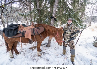 NOVEMBER 10 2017 - DILLON, MT: Mature Adult Man With Horse Packed With Deer Hunting Gear, Preparing To Ride In The Montana Wilderness On A Snow Covered Trail In The Winter