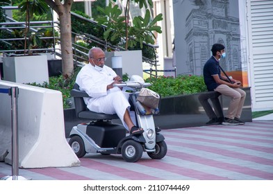 November 13, 2021 UAE, Dubai.  Indian Old Man In A Medical Mask And White Clothes Is Resting In A Scooter On The Street.