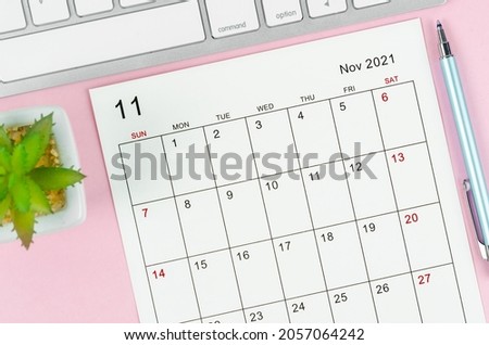 November 2021 calendar sheet with keyboard computer on pink background.