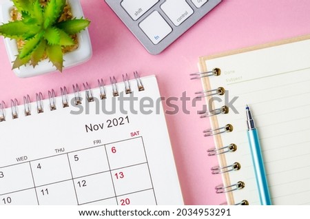 November 2021 desk calendar with keyboard computer on pink background.