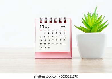 November 2021 Desk Calendar With Small Tree On Wooden Table.