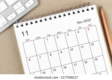 November 2022 desk calendar with pencil on wooden background.