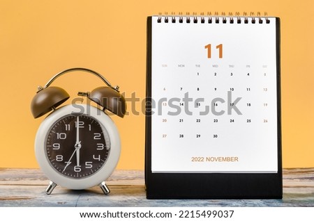 November 2022 Monthly desk calendar for 2022 year and Alarm clock vintage on wooden table. Photo stock © 