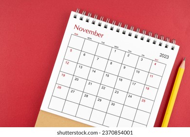 November 2023 desk calendar and pencil on red color background. - Powered by Shutterstock