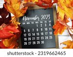November 2023 monthly calendar with maple leaf on wooden background