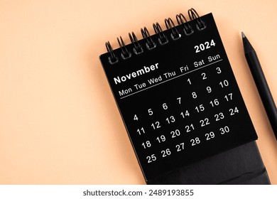 November 2024 Black spiral desktop calendar and wooden pencil on yellow background. - Powered by Shutterstock