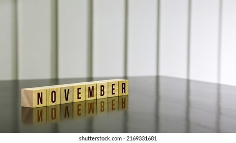 NOVEMBER Word On Wooden Cube On Black Gloss Wooden Table. Selected Focus.