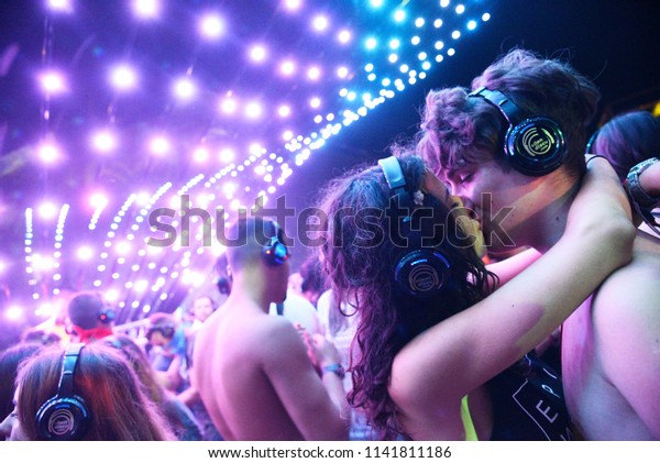 NOVI SAD, SERBIA - JULY 9,\
2017: Young couple kissing enjoying silent disco stage at Exit\
festival on July 7, 2017 in Petrovaradin fortress in Novi Sad,\
Serbia