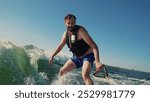 A novice athlete falls from a wakeboard while riding at high speed. Water sprays up, showing a moment of loss of balance and adrenaline. The scene reflects the risk and dynamics of water extreme sport