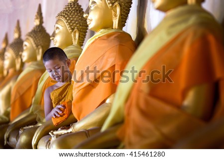 Novice munk cleaning golden Buddha with love and faith