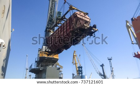 Novorossiysk, Russia - August 11, 2016: Moving freight railway car in the port by a port crane. Cargo lifting operations. Industrial port.