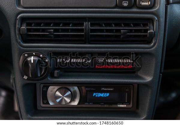 Novosibirsk, Russia - 05.20.2020: plastic panel of\
central unit is black in color with Pioneer music radio with blue\
display and round metallic chrome volume control knob, and a\
climate control\
system