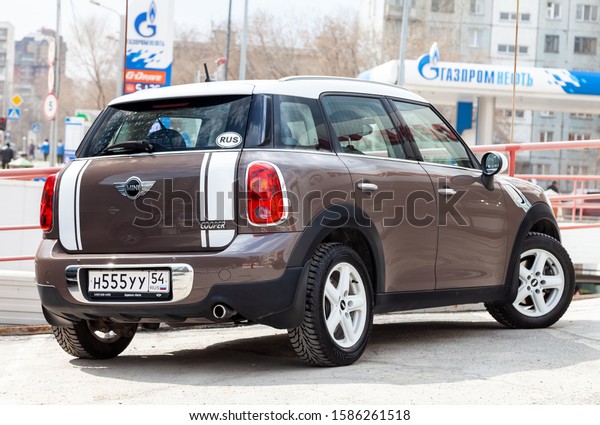 Novosibirsk,\
Russia - 06.26.2019: An expensive car, a female model of a mini\
cooper countryman beige and gold color and a white roof polished\
and shiny is set up in a street parking\
