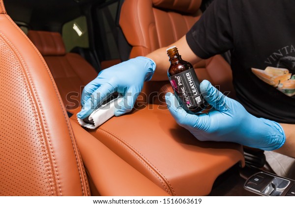Novosibirsk, Russia - 08.01.2018: Applying a\
nano-ceramic coating for interior Ceramic Pro Leather 9h and Light\
on the car\'s seat brown upholstery by a worker with a sponge and\
chemical\
composition