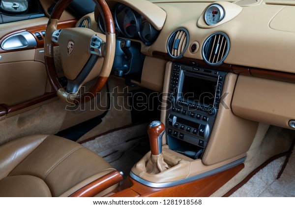 Novosibirsk, Russia - 08.01.2018: The interior of\
an expensive sportcar coupe Porsche Boxster S 2006 inside the front\
seats of genuine perforated leather the central control panel with\
wood and chrome