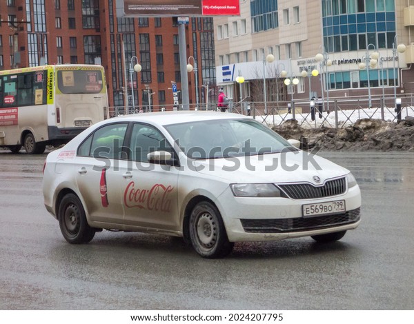 Novosibirsk, Russia - April 05 2021: private fwd white\
metallic color new cheap economy european budget popular sedan made\
in Czech car Skoda Rapid owned Coca-Cola, bestseller driving on\
urban street 