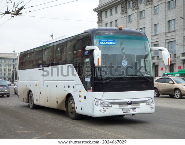 Novosibirsk, Russia - April 05 2021: white\
metallic color big chinese new touristic tour bus Yutong ZK6122,\
private transfer service vehicle made in China driving on urban\
town dirty unclean\
street