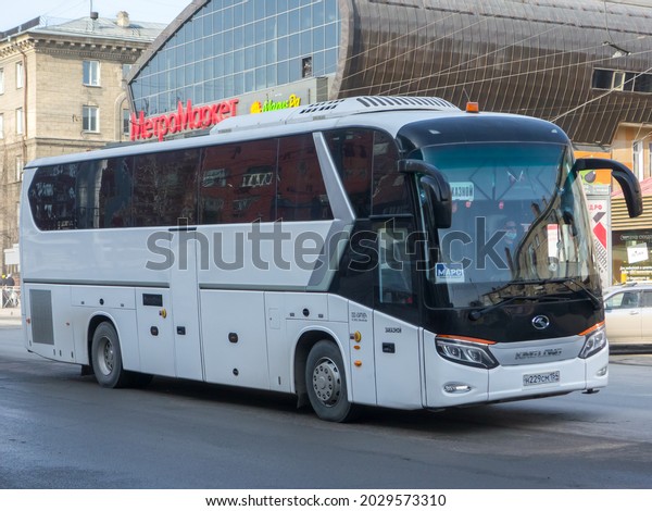 Novosibirsk, Russia - April 08 2021: white\
metallic color big chinese new touristic tour rental bus King Long\
XMQ 6129 Y, private transfer service vehicle made in China driving\
on urban town\
street