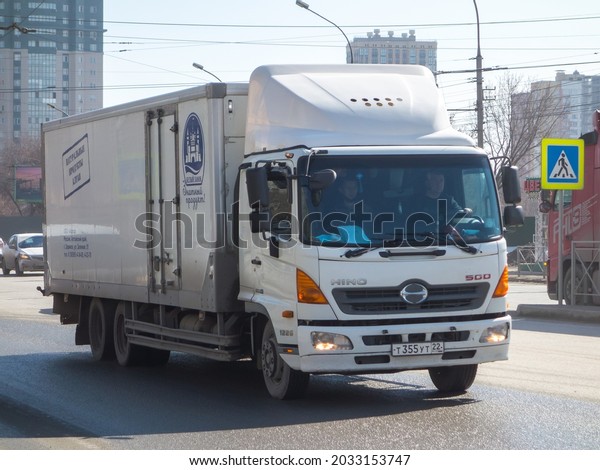 Novosibirsk, Russia - april 14 2021:  white color\
japanese box truck car chassis Hino 500 Series Altai Natural\
Products owned, new popular small cargo mini truck made in Japan\
drive on urban street\
