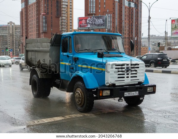 Novosibirsk, Russia - april 28 2021: private blue\
metallic color heavy frame small russian dump truck chassis ZIL MMZ\
45085, old vintage classic car made in russia driving on urban\
spring wet street
