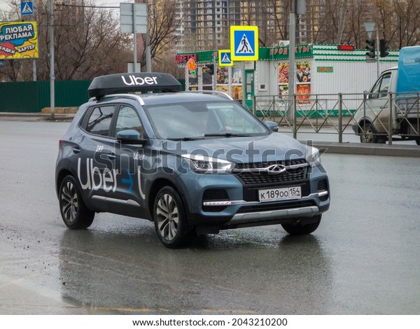 Novosibirsk, Russia - april 28 2021: private awd\
cheap blue gray metallic color chinese hatch new Chery Tiggo 4, car\
taxi service Uber livery, SUV crossover drive on sleet slush wet\
street after rain