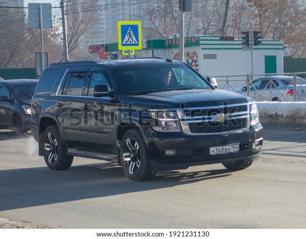Novosibirsk, Russia - February 02 2021: private\
awd black metallic color all-wheel drive american fullsize frame\
heavy SUV Chevrolet Tahoe, popular big car made in USA on winter\
dirty unclean\
street