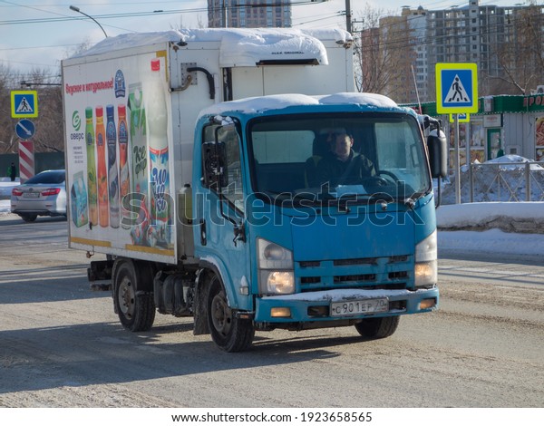 Novosibirsk, Russia - february 04 2020: blue small\
refrigerator japanese small truck of food dairy products company\
Overs - Isuzu N-Series, painted print on box, on the winter sunny\
urban street