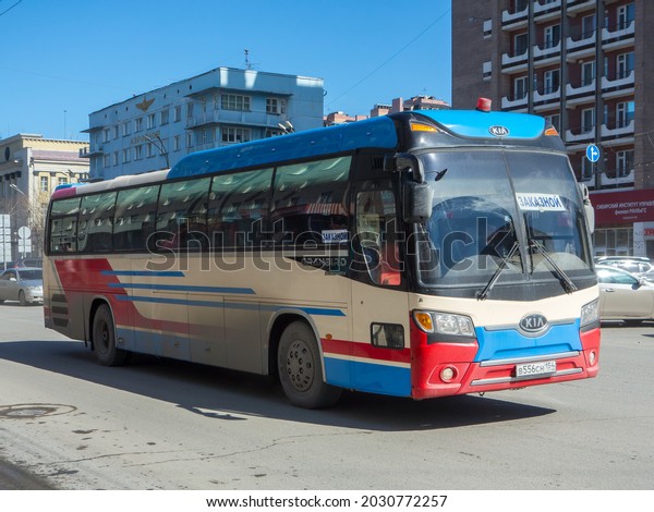 Novosibirsk, Russia - february 04 2020: private\
white red blue metallic color multicolor rental old South Korean\
tourist delivery bus Kia Granbird Parkway, drive route on urban\
broad city sunny\
street