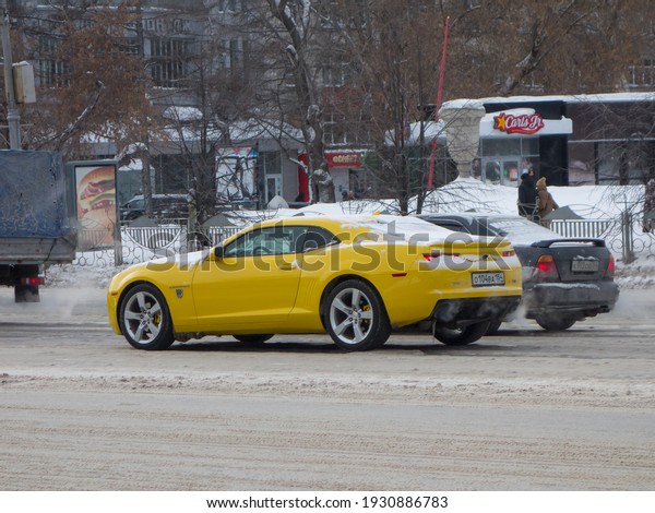 Novosibirsk, Russia - February 09 2021: private\
rear-wheel drive\
yellow metallic north american sport coupe\
Chevrolet Camaro, popular USDM US-spec muscle car exported from USA\
on the winter\
street