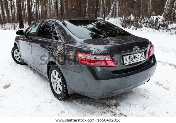 Novosibirsk, Russia – February 10,\
2020:   black Toyota Camry, back  view.  Photography of a modern\
popular sedan  made in Japan standing on a snowy street in\
winter
