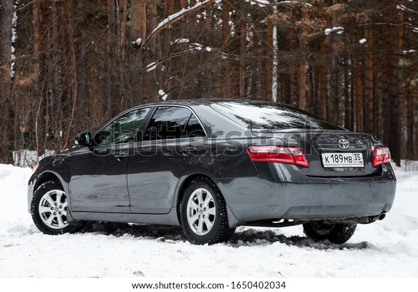 Novosibirsk, Russia – February 10,\
2020:   black Toyota Camry, back  view.  Photography of a modern\
popular sedan  made in Japan standing on a snowy street in\
winter
