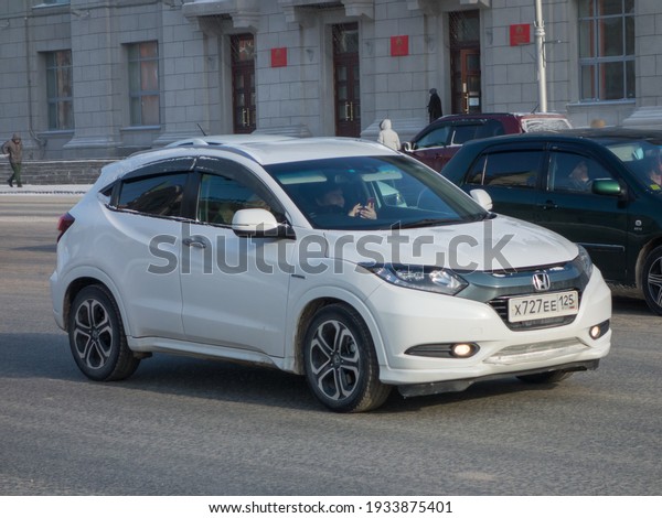 Novosibirsk, Russia - February 11 2021: private\
white metallic color japanese small crossover SUV Honda Vezel\
Hybrid, all-wheel car, export import from Japan, driving in snow\
winter steet