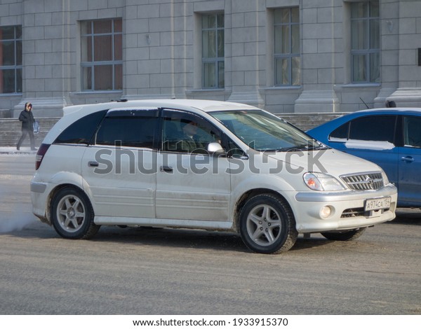 Novosibirsk, Russia - february 11 2021: private\
all-wheel drive white metallic color passenger japanese minivan car\
Toyota Nadia Type SU, station wagon van from Japan going driving\
the winter street
