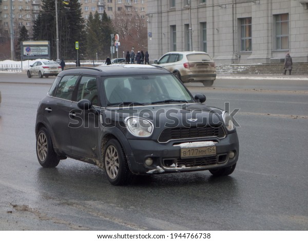 Novosibirsk, Russia - February 16 2021: private\
all-wheel drive black metallic british small SUV Mini Cooper\
Countryman All4 R60, car crossover exported from UK driving on\
dirty wet sleet road\
street