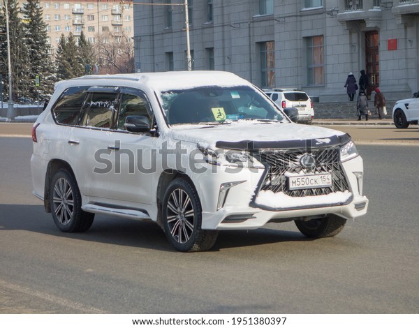 Novosibirsk, Russia - February 18 2021: private\
all-wheel drive white metallic color, japanese big frame luxury SUV\
Lexus LX 570 Superior, popular car crossover going on the broad\
street in city