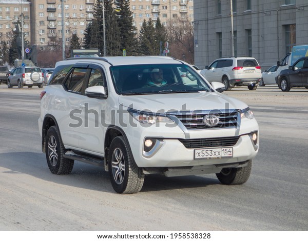 Novosibirsk, Russia - February 25 2021: private\
all-wheel drive 4x4 white metallic color japanese frame midsize SUV\
Toyota Fortuner, popular new offroad car crossover driving on\
winter snow street\
