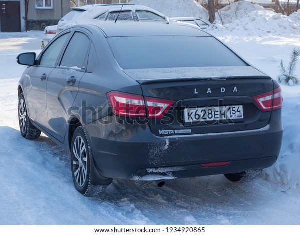 Novosibirsk, Russia - fubruary 12 2021: private\
brown black metallic color new cheap economy sedan russian car VAZ\
Lada Vesta Exclusive limit version parking on the winter snow\
street in the\
morning