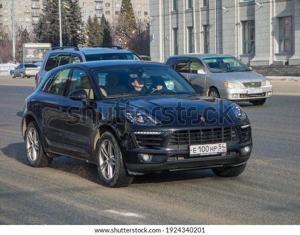 Novosibirsk, Russia - fubruary 4 2021: private\
all-wheel drive black metallic color compact sport fast coupe\
crossover Porsche Macan 95B, made in Germany luxury awd 4wd SUV car\
on winter dirty\
street