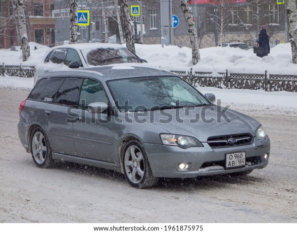 Novosibirsk, Russia - march 01 2021: private awd all\
wheel drive dark silver gray metallic color japanese station wagon\
car Subaru Legacy, export import from Japan driving on snow winter\
street 