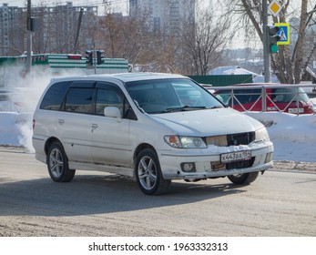 Novosibirsk, Russia - March 02 2020: Private White Metallic Color Passenger Japanese Minivan Old Car Nissan Presage, Station Wagon Van Mini Bus Export From Japan Driving On Snow Winter Morning Street 