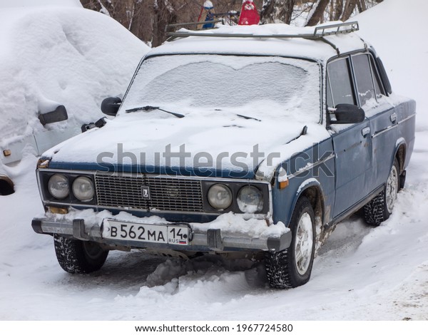 Novosibirsk, Russia - march 05 2020: dark blue\
metallic color russian rwd drive old classic sedan VAZ Lada 2106\
Zhiguli, started to be released soviet union parking on the snow\
winter street in\
yard