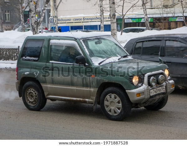 Novosibirsk, Russia - march 05 2021: private awd\
all-wheel drive green metallic color japanese old 90s subcompact\
crossover 4x4 4wd Mitsubishi Pajero Mini, key car SUV driving on\
winter snow street